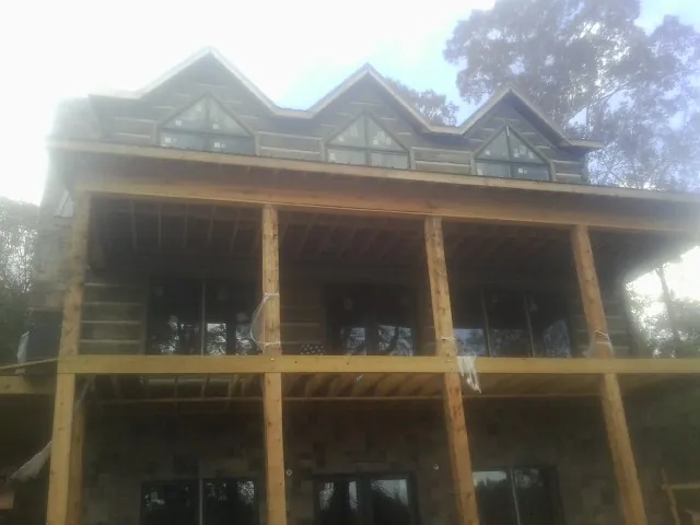 Dormers and porch framing on a large log home under construction — Roof Coating work by our crew in Belle Glade