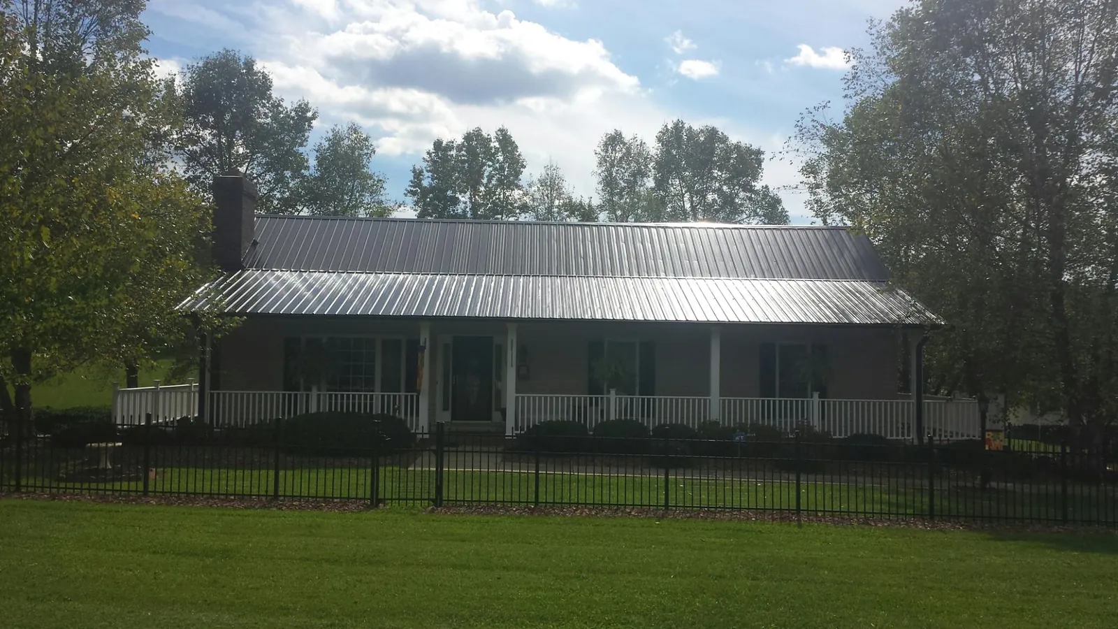 Gray metal roof on a brick ranch with a full width front porch — Gutter Guard Installation work by our crew in Belle Glade