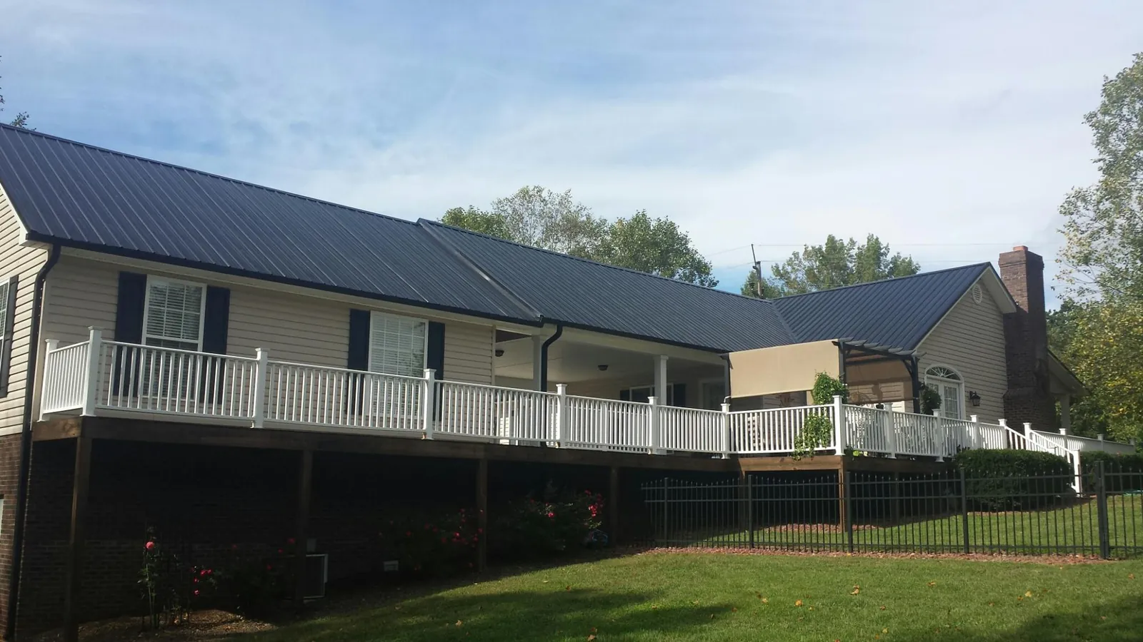 Black metal roof above a long white railed deck on a hillside home in Belle Glade