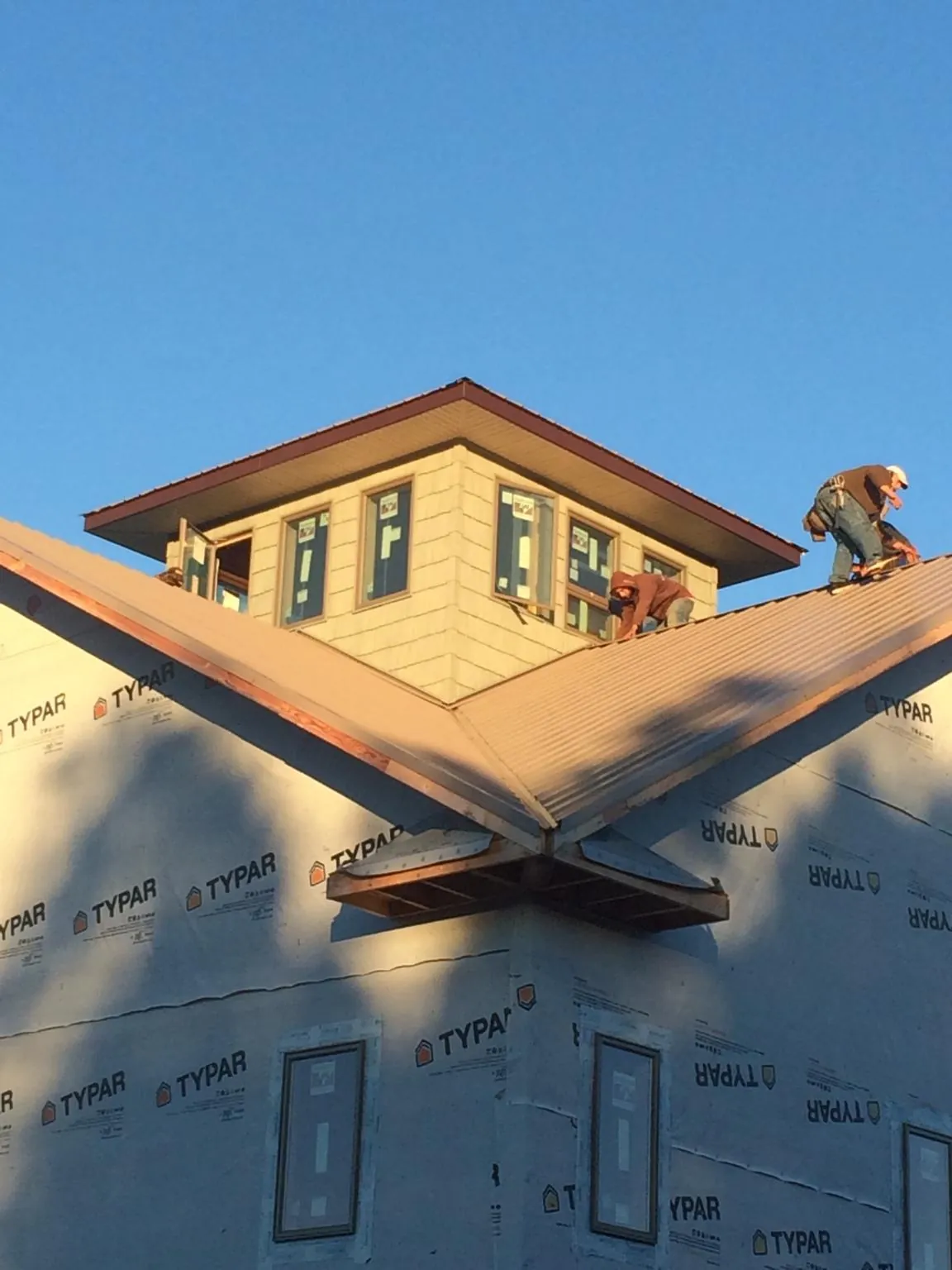 Roofers working around a rooftop cupola on a new metal roof at sunset — Roof Waterproofing in Belle Glade by Roofing Brothers